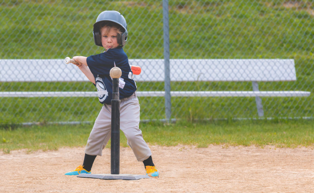 Kid hitting ball on t ball stand