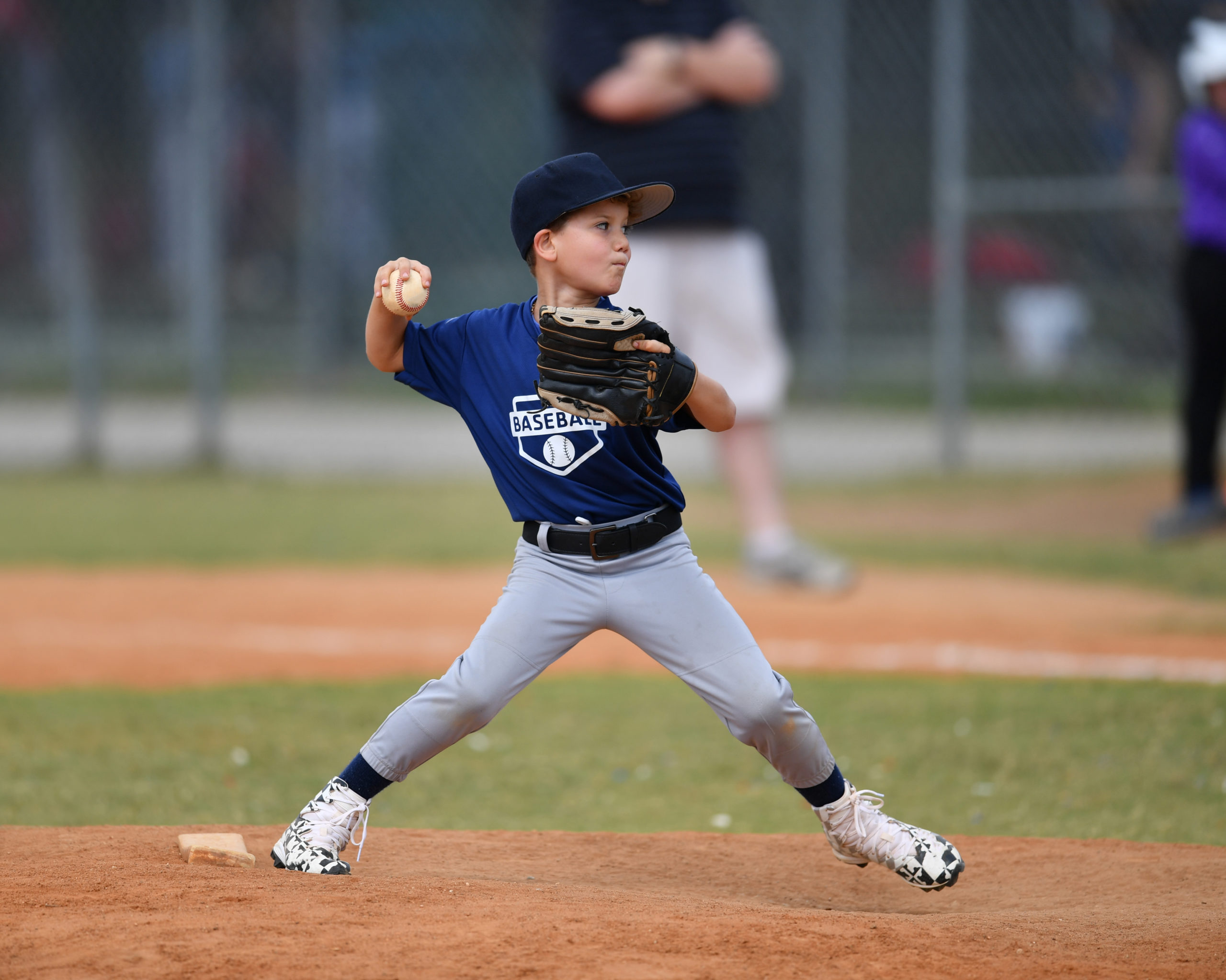 Young boy pitching the ball in a baseball game Young baseball pitcher in wind up about to through the ball